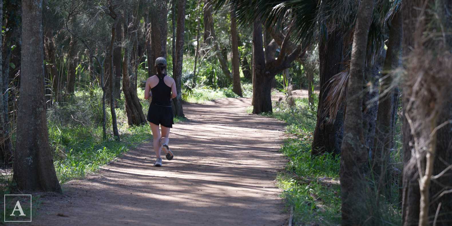 Woman running on the exercise and walking trail around Narrabeen Lagoon Woman running on the exercise and walking trail around Narrabeen Lagoon